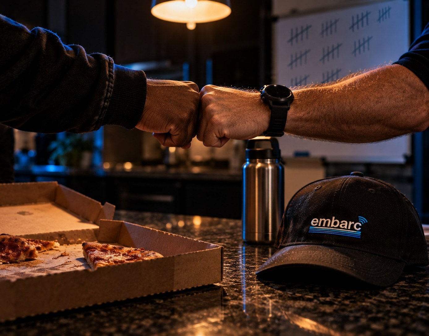 Two Embarc reps fist bumping over pizza at the crew house after a day on doors
